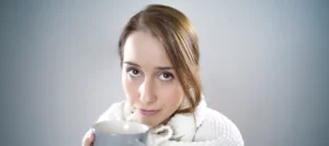 a woman who got a cold, holding a cup to keeping worm